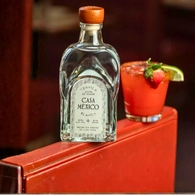 Bottle of Casa Mexico Blanco Tequila next to a cocktail